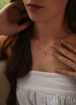 Close-up of a person wearing gold necklaces with a diamond heart pendant