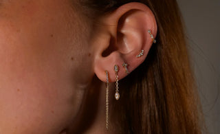 The Bond Society minimalist gold rings and hoop earrings styled on woman with sleek hair, showcasing elegant fine jewelry design.