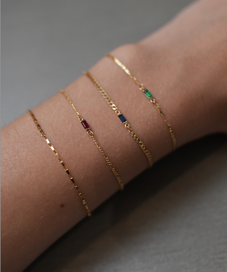 The Bond Society gold chain bracelets with colorful gemstone accents in red, blue, and green, minimalist fine jewelry design.