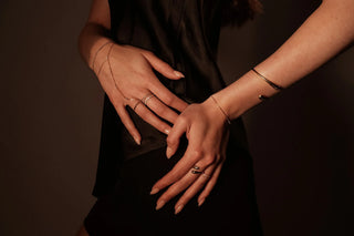 Minimalist gold cuff bracelets on woman's crossed arms, modern jewelry fashion photography with soft natural light.