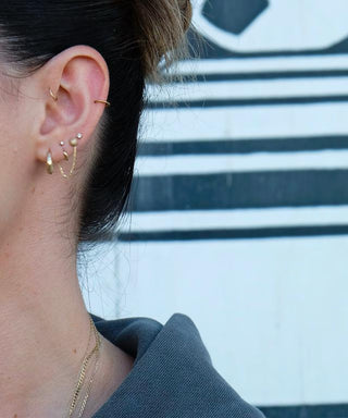 The Bond Society gold hoop and stud earrings styled in curated ear stack with pearls, modern minimalist jewelry look.