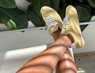 The Bond Society minimalist gold anklet styled with white trousers and black wedge sandals, elegant everyday jewelry accessory.