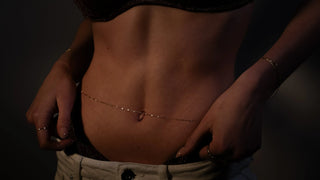 The Bond Society delicate gold body chain styled on woman’s waist, minimalist fine jewelry for modern elegant look.