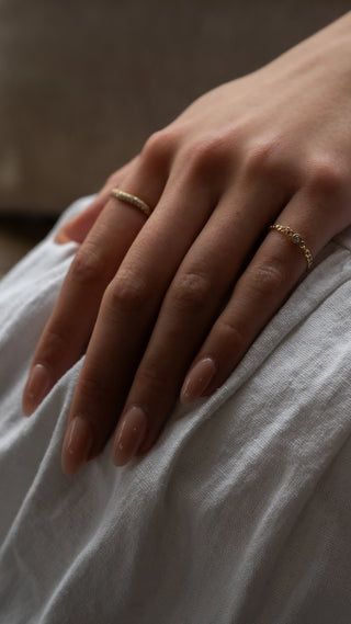 The Bond Society dainty gold rings on woman's hand with natural nude manicure, minimalist fine jewelry styling.