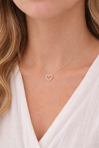 Bezel-set diamond heart pendant on a 14k gold chain, worn layered