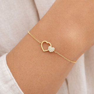 Two pavé diamond hearts on a dainty 14k gold chain bracelet, worn on wrist