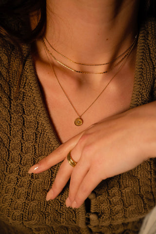Women wearing a solid gold delicate evil eye pendant with diamond.