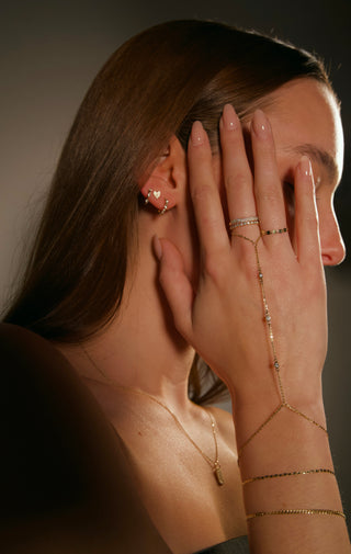 Woman wearing gold jewelry including earrings, necklaces, bracelets and hand chain